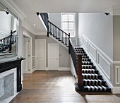Striped carpet on stairs in hallway with mouldings on walls