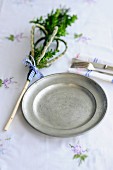 An Easter place setting with a pewter plate, cutlery and boxtree decoration