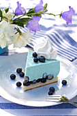 Slice of blueberry mousse tart on table set in blue and white