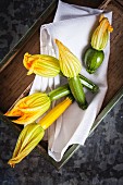 Courgette flowers on a cloth in a wooden crate
