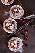 Mini shortcrust pies with cherries and icing sugar (seen from above)