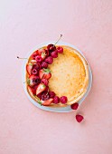 Cheesecake with fresh berries on a coloured surface (seen from above)