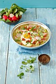 Sorrel and cress soup with potatoes, fried egg, bacon and red radishes