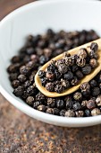 A bowl of black peppercorns (close-up)