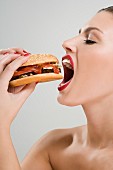 A young woman passionately biting into a hamburger