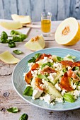 Melon salad with feta cheese, Parma ham, basil leaves and dressing