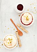 Scoops of ice cream served with pistachio nuts, red fruit coulis and wafer rolls