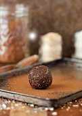 A date energy ball being rolled in cocoa powder