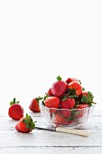 Fresh strawberries in a glass dish and next to the dish