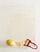Potatoes, potato peelings and a peeler