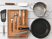 Various kitchen utensils: pans, a pot, a spatula, cutlery and a brush