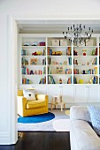 Yellow armchair in front of a shelf with colorful books and toys