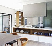 Island counter below extractor hood and open shelves seen past dining table
