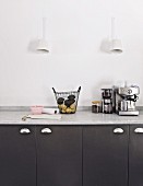 Sconce lamps above black kitchen cupboards with marble worksurface