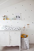 Changing mat on top of white cabinet against white wall decorated with black stickers