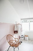 Cane chair and women's clothing on white clothes rail in attic room