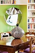 Black and white striped vase on wooden table in front of mirror