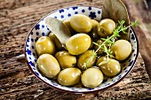 Pickled green olives with a sprig of thyme
