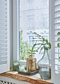 Fensterbrett aus rustikalem Eichenholz mit Vasen und Teelichtgläsern dekoriet, an Fenster romantische Häkelspitze