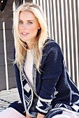 Junge blonde Frau in Top und blau-weisser Strickjacke