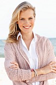 A young blonde woman wearing a white blouse and a dusty pink cardigan