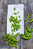 Edamame beans on a piece of paper and on a wooden surface