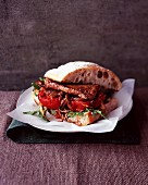 A steak sandwich with tomatoes and rocket