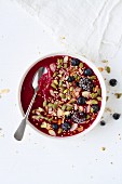 A berry smoothie bowl with pumpkin seeds, sesame seeds and almonds