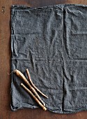 Three fresh black salsify on a cloth (seen from above)