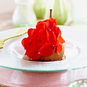 A poached pear with rose petals