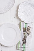 Drei verschiedene weiße Teller und Silbergabeln auf Stoffserviette