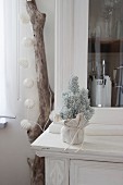 Small Christmas tree sprayed with artificial snow and wrapped in fabric