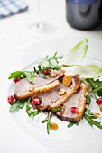 Sliced duck breast with pomegranate seeds and sultanas