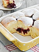 Baked sweet yeast dumplings with raspberry jam dusted with icing sugar