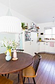 Retro vases on round dining table and view into open-plan kitchen