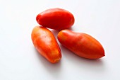 Three plum tomatoes on a white surface