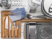 Kitche utensils: a handheld mixer with dough hooks, a chopper, a salad spinner, a measuring jug, a box grater, spoons, knives and a whisk