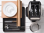 Assorted kitchen utensils: cutlery, crockery, a baking tray and a toaster
