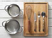 Assorted kitchen utensils: saucepans, cutlery and a whisk