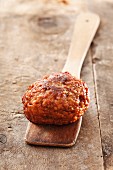 A meatball on a wooden spoon