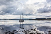 Segelboot an schottischer Küste bei bewölktem Himmel