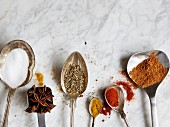 Spoons with assorted spices on a marble surface