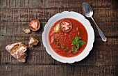 Tomato soup with spring onions, fresh basil, sliced tomatoes and olive oil