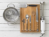 Assorted kitchen utensils: a saucepan, a measuring cup, a grater, cutlery and a hand liquidiser
