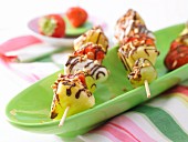 Fruit kebabs with chocolate and chopped almonds