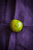 A green zebra tomato on a violet cloth