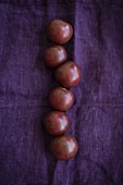 Six black tomatoes on a violet cloth