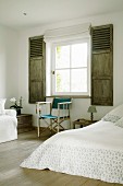 Director's chair on wooden floor in rustic bedroom with interior shutters