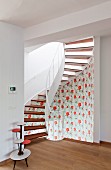 Spiral staircase decorated with retro-style floral wallpaper
