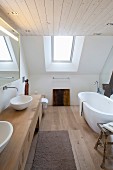 Modernes Designerbad mit freistehender weißer Badewanne und maßgefertigtem Waschtischmöbel in Dachgeschoss